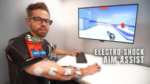 EMS-powered neuromuscular aim assist setup showing electrodes and controller on a gaming desk