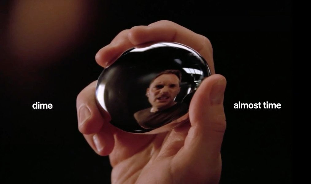 A still-like view of a stone-shaped gadget and earbud pieces shown in the leaked Dime-style promo.
