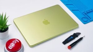 Technician lifting the 36.5Wh MacBook Neo battery after removing screws, with very little adhesive residue visible.