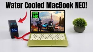 MacBook Neo on a desk with external liquid cooling attached, showing tubing and a compact radiator module.