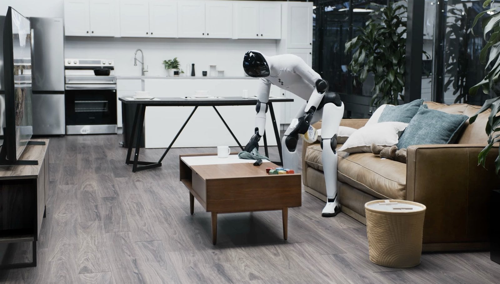 Figure’s Helix 02 humanoid robot tidies a living room, picking up scattered items and placing them in bins.