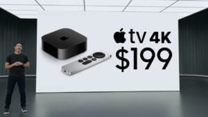 The current generation Apple TV 4K streaming box resting next to a television set.