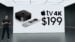 The current generation Apple TV 4K streaming box resting next to a television set.