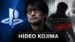 Hideo Kojima standing on a stage speaking into a microphone.
